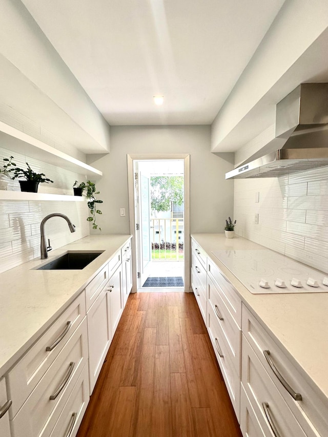 kitchen with dark hardwood / wood-style flooring, sink, decorative backsplash, wall chimney range hood, and white cabinets