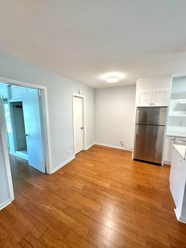 interior space with stainless steel fridge, white cabinets, and light hardwood / wood-style floors