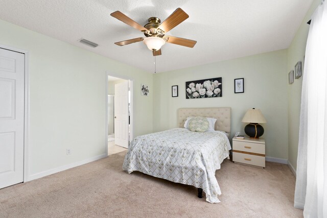 bedroom with a textured ceiling, light colored carpet, and ceiling fan