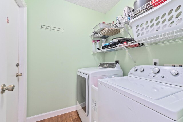 laundry area featuring washer and clothes dryer, wood-type flooring, and a textured ceiling