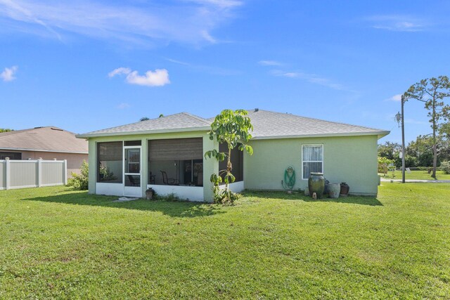 rear view of property with a lawn and a sunroom