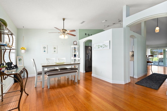 dining area featuring a textured ceiling, hardwood / wood-style flooring, high vaulted ceiling, and ceiling fan