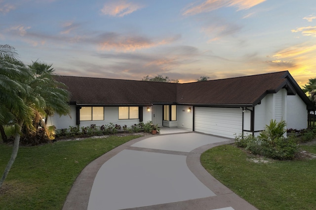 ranch-style house featuring a garage and a yard