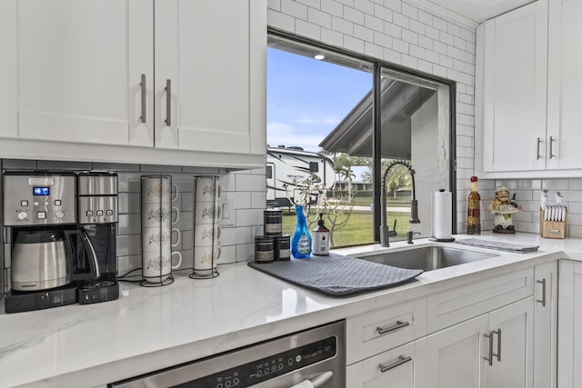 kitchen featuring sink, light stone countertops, white cabinets, and tasteful backsplash