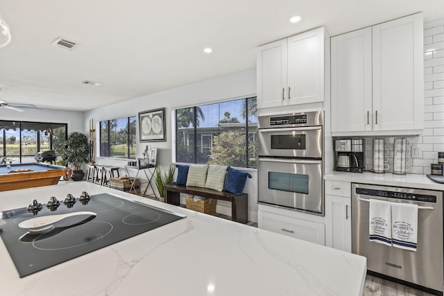 kitchen with ceiling fan, stainless steel appliances, white cabinetry, and a healthy amount of sunlight