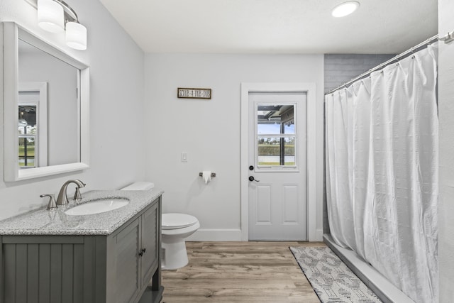 bathroom with hardwood / wood-style floors, toilet, vanity, and curtained shower