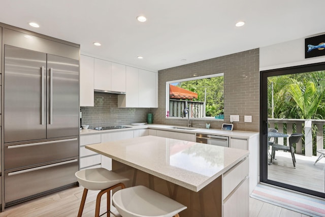 kitchen featuring light wood-type flooring, a kitchen island, sink, appliances with stainless steel finishes, and white cabinets