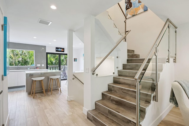 stairway with hardwood / wood-style floors and sink