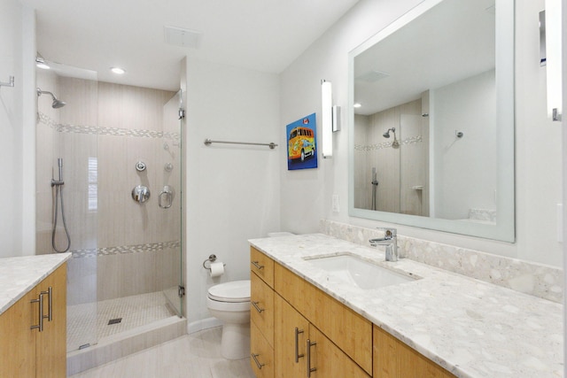 bathroom with tiled shower, vanity, toilet, and tile patterned flooring