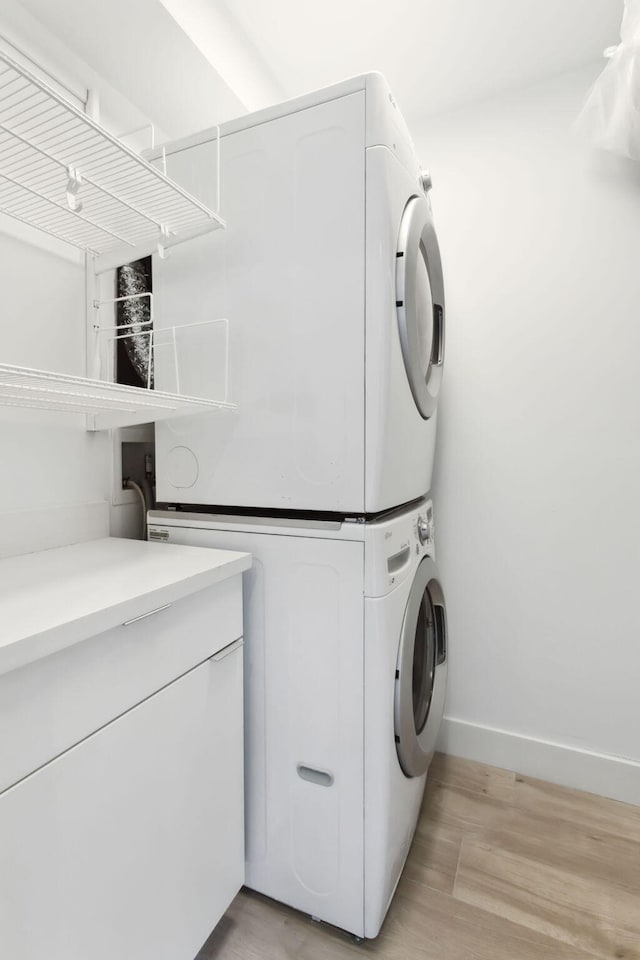 laundry area featuring light wood-type flooring and stacked washer and clothes dryer