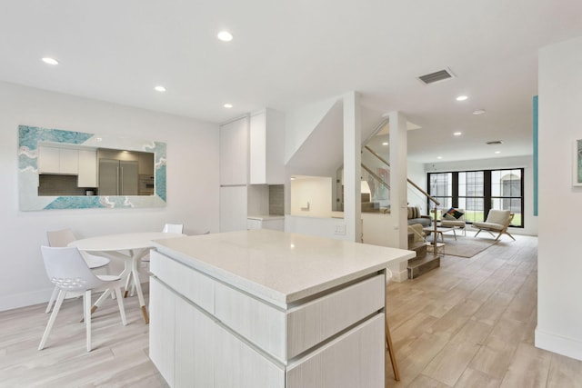 kitchen featuring a breakfast bar, white cabinets, and light hardwood / wood-style floors