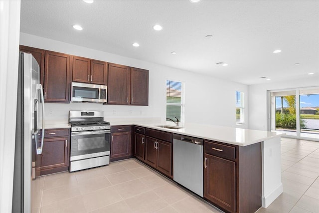 kitchen featuring a textured ceiling, stainless steel appliances, sink, kitchen peninsula, and light tile patterned flooring