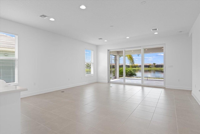 tiled spare room with a water view and a textured ceiling