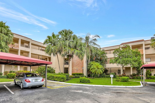 view of property featuring covered and uncovered parking