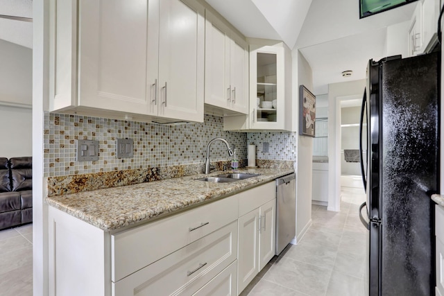 kitchen with a sink, backsplash, freestanding refrigerator, white cabinets, and dishwasher