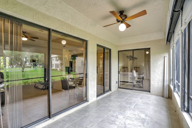 unfurnished sunroom featuring ceiling fan and a wealth of natural light