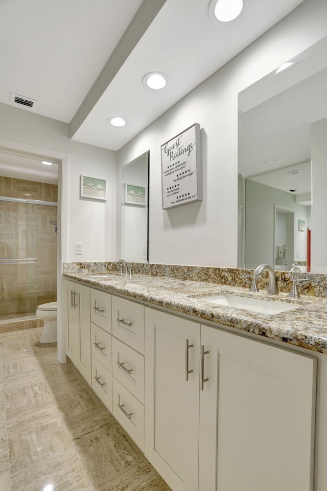 bathroom with tile patterned flooring, a shower with door, vanity, and toilet