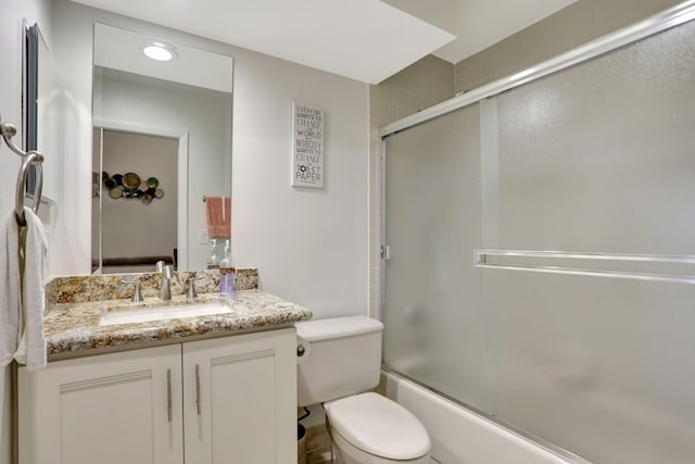 full bathroom with combined bath / shower with glass door, toilet, and vanity