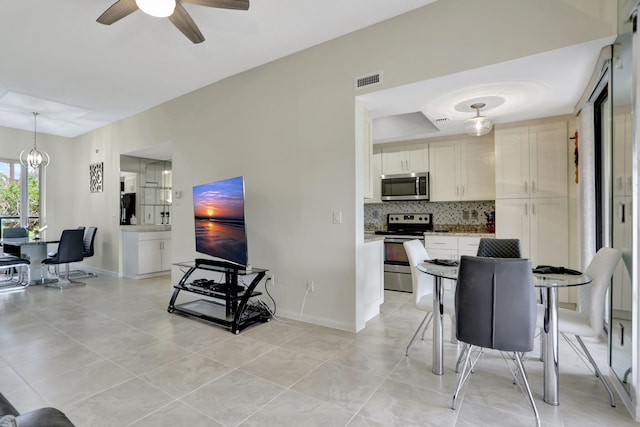 tiled living room featuring ceiling fan with notable chandelier