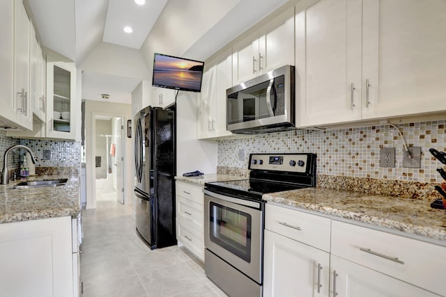 kitchen with appliances with stainless steel finishes, white cabinetry, tasteful backsplash, sink, and light tile patterned floors