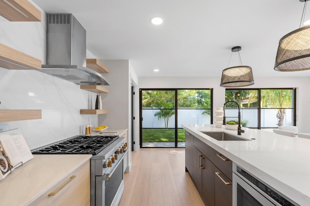 kitchen featuring decorative light fixtures, wall chimney exhaust hood, plenty of natural light, and stainless steel appliances