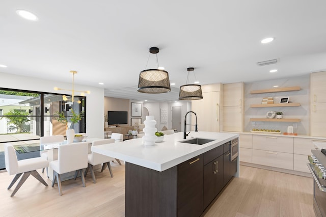 kitchen with hanging light fixtures, dark brown cabinets, light hardwood / wood-style floors, and sink