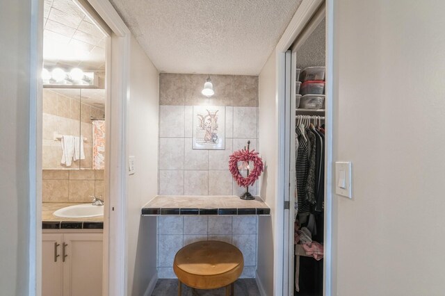 bathroom with tile walls, a textured ceiling, and vanity