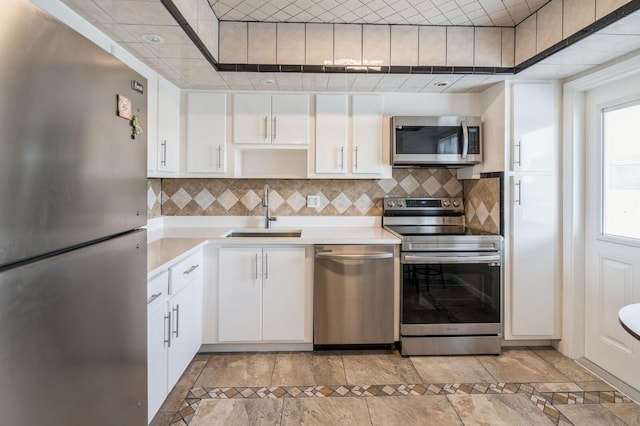 kitchen featuring sink, a healthy amount of sunlight, light tile patterned floors, stainless steel appliances, and white cabinets