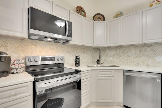 kitchen featuring stainless steel appliances, sink, decorative backsplash, and white cabinetry