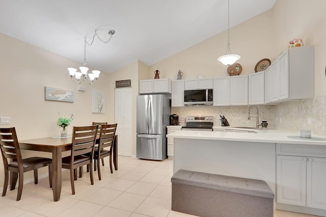 kitchen with a chandelier, sink, vaulted ceiling, appliances with stainless steel finishes, and decorative light fixtures