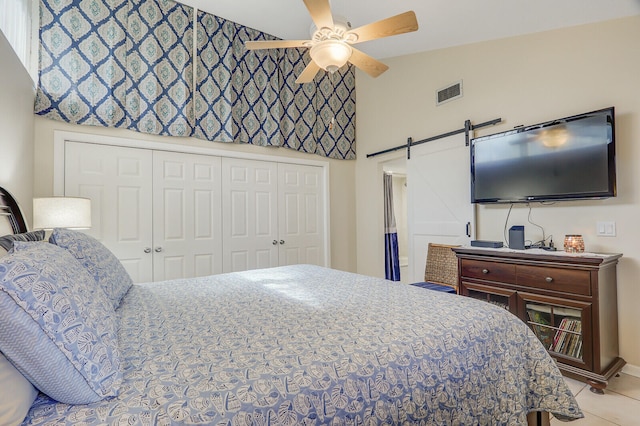 tiled bedroom with a closet, ceiling fan, and a barn door