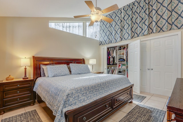 tiled bedroom with high vaulted ceiling, ceiling fan, and multiple closets