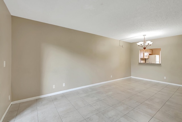 empty room featuring light tile patterned floors, a chandelier, and a textured ceiling