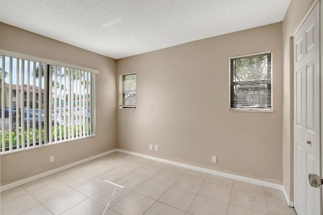 empty room featuring light tile patterned floors and a textured ceiling