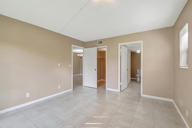 unfurnished bedroom featuring a closet, visible vents, a spacious closet, and baseboards