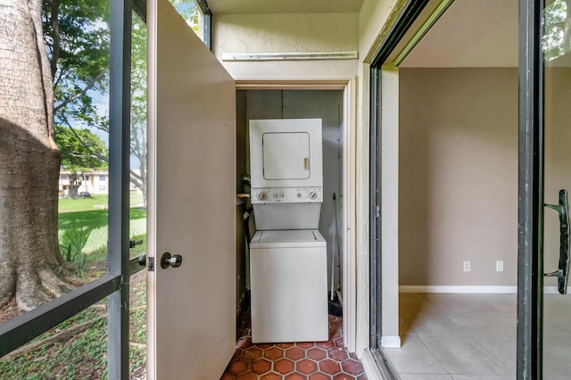 laundry area featuring laundry area, tile patterned flooring, baseboards, and stacked washer / dryer