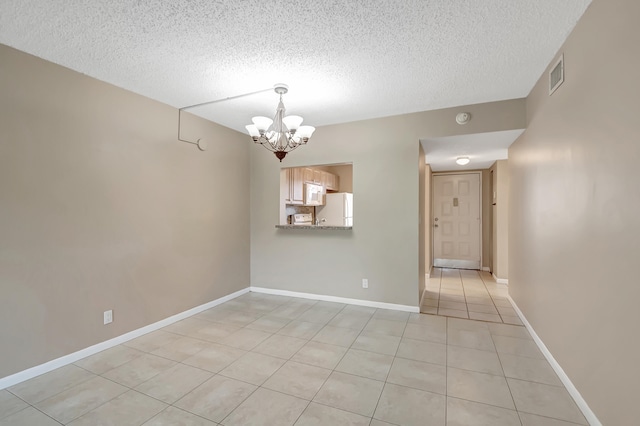 tiled empty room with a textured ceiling and a notable chandelier