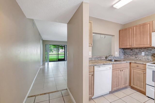 kitchen featuring light brown cabinetry, light tile patterned floors, white appliances, sink, and a textured ceiling