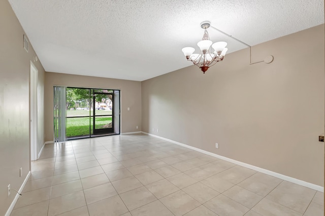 empty room with a chandelier, visible vents, a textured ceiling, and baseboards