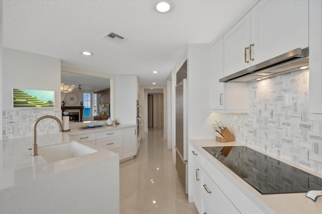 kitchen with white cabinetry, sink, backsplash, and a textured ceiling