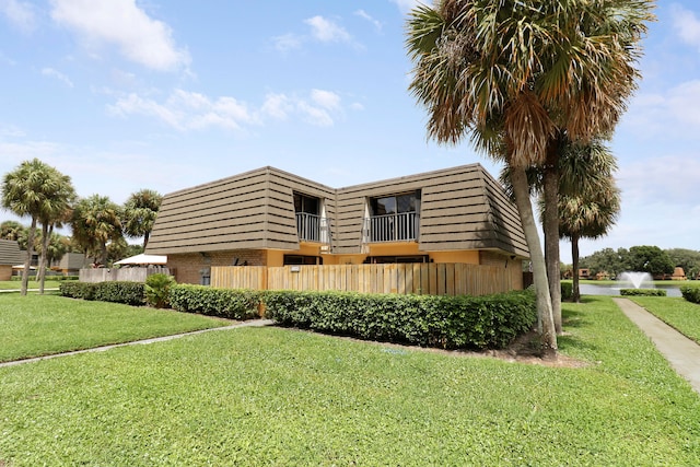 view of front facade featuring a balcony and a front yard