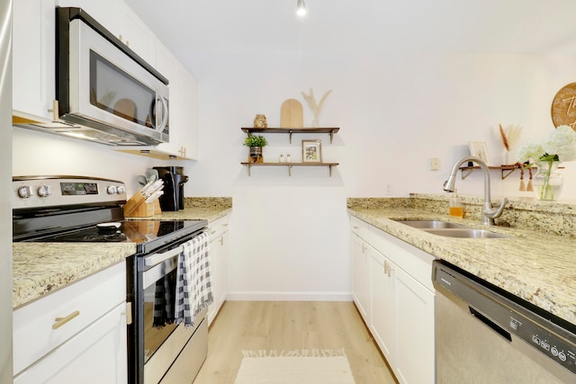 kitchen featuring light wood-type flooring, stainless steel appliances, light stone counters, sink, and white cabinets