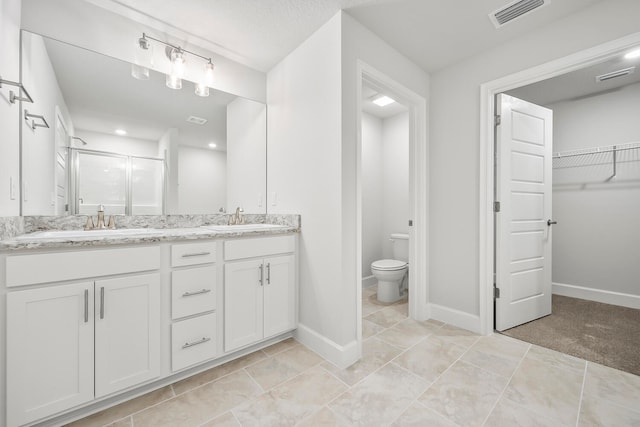 bathroom featuring tile patterned flooring, vanity, toilet, and a shower with door