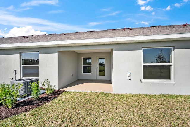 rear view of property featuring a lawn, a patio area, and central AC