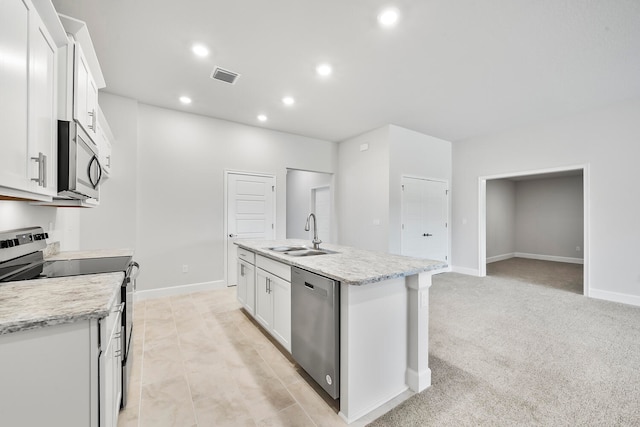 kitchen with white cabinets, sink, stainless steel appliances, and an island with sink