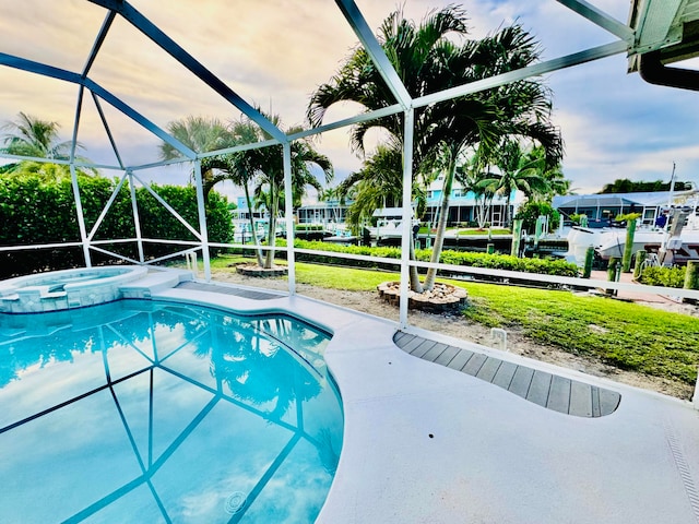 pool at dusk featuring glass enclosure and an in ground hot tub