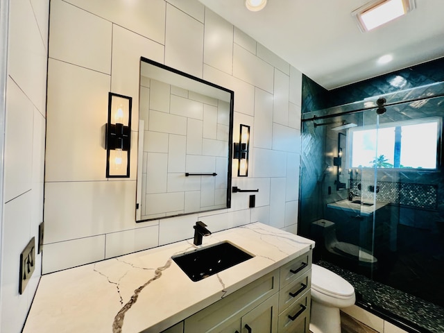 bathroom with walk in shower, tile walls, vanity, and toilet