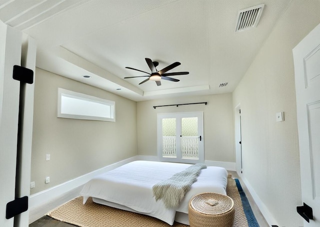 bedroom with ceiling fan, hardwood / wood-style flooring, and a tray ceiling