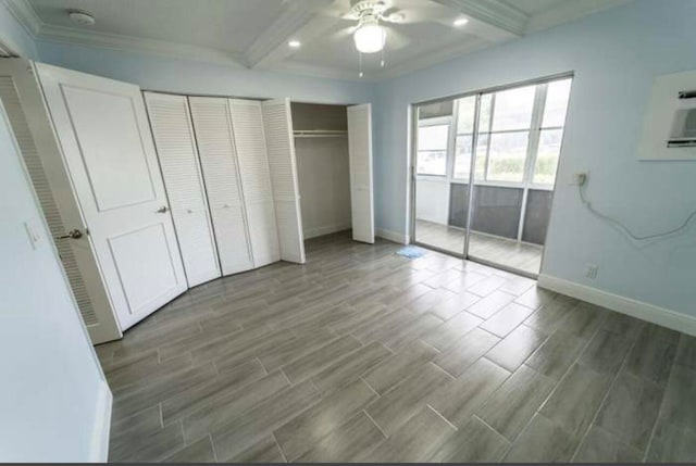 unfurnished bedroom featuring ceiling fan, beamed ceiling, dark hardwood / wood-style floors, multiple closets, and crown molding