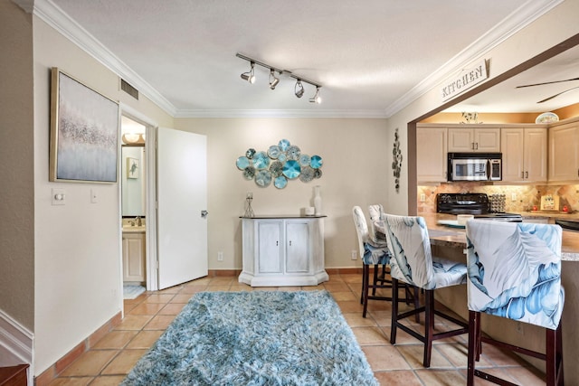 dining space with track lighting, light tile patterned floors, crown molding, and a textured ceiling